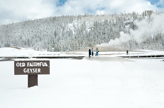 Old Faithful winter – Yellowstone National Park a sign on the side of a snow covered field