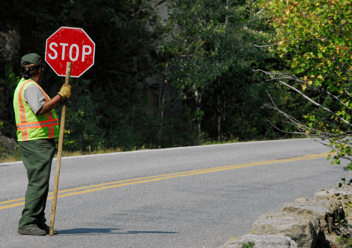 88ca4f894764e8c a man holding a stop sign on the side of a road