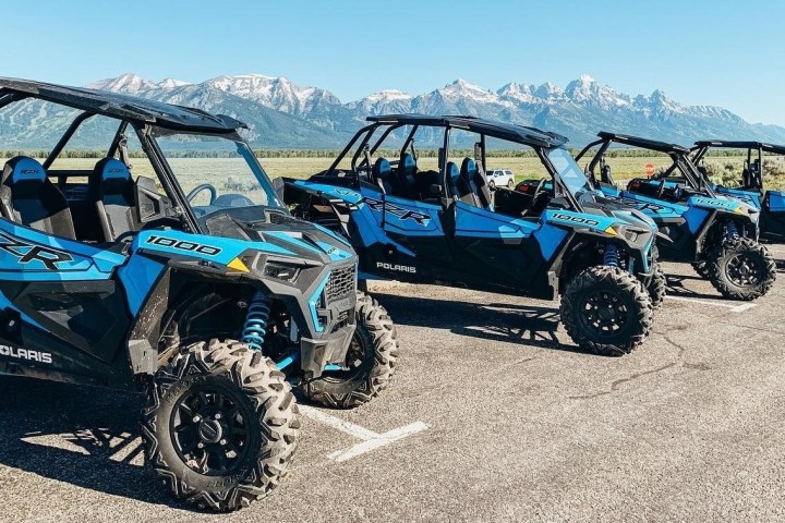 a tractor in front of a blue car on a dirt road