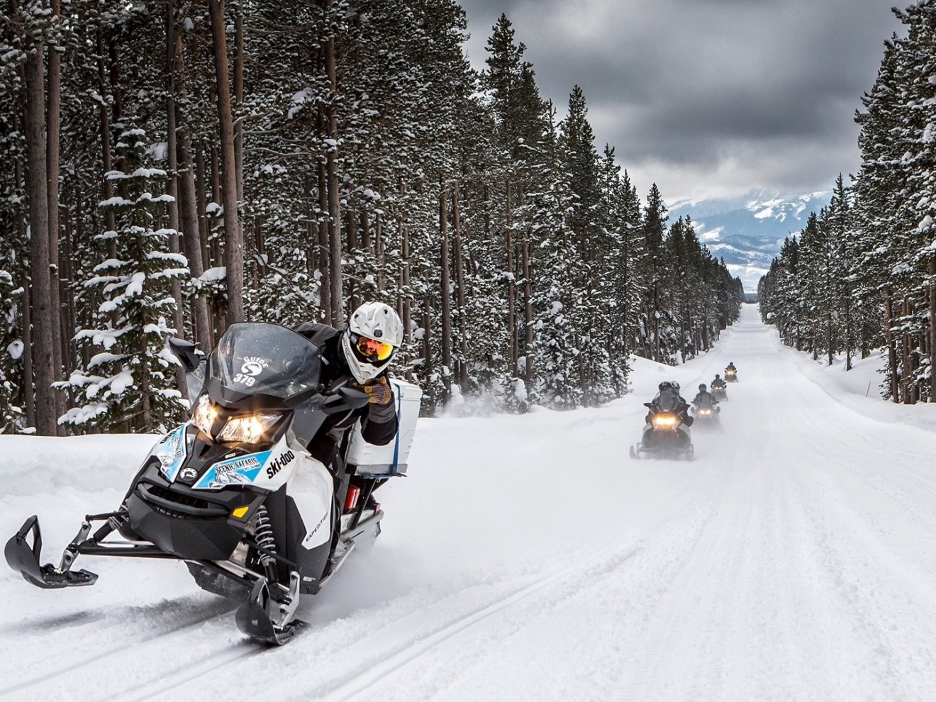 a group of people riding skis down a snow covered slope
