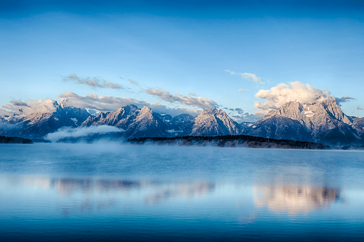 a group of clouds in front of a mountain